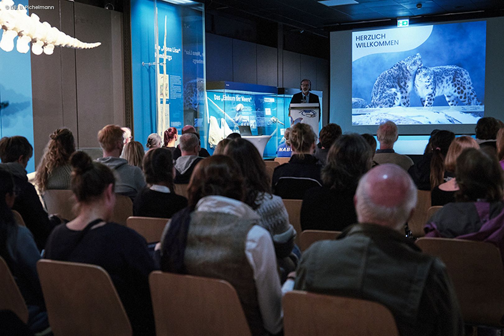 Zuhörende lauschen Vortrag in der Ausstellung