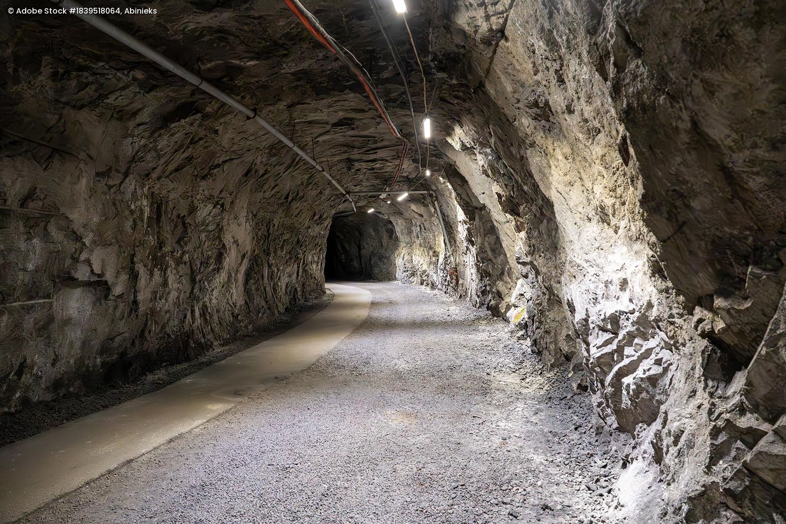Tunnel in einer Eisenerzmine mit unregelmäßigen Felswänden und Beleuchtung an der Decke