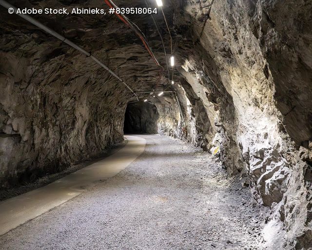 Tunnel in einer Eisenerzmine mit unregelmäßigen Felswänden und Beleuchtung an der Decke