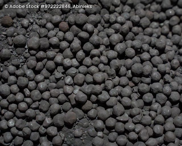 Nahaufnahme von kugelförmigen Eisenerzpellets mit unregelmäßiger Oberfläche