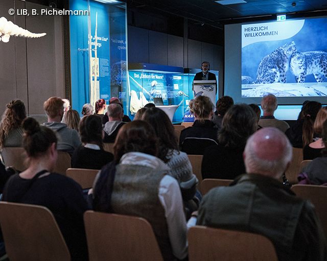 Zuhörende lauschen Vortrag in der Ausstellung