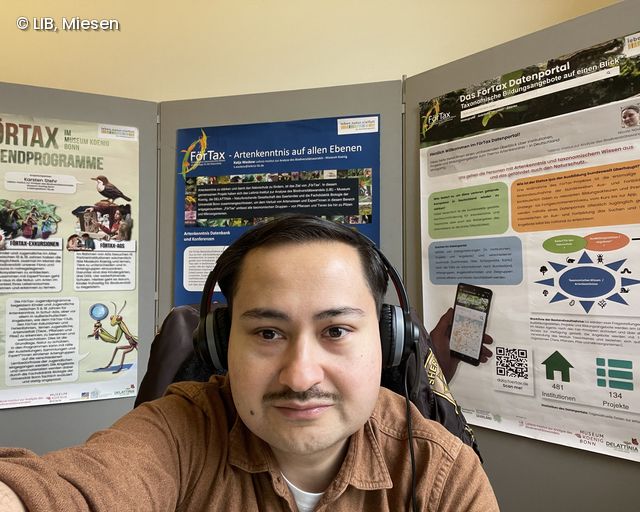 Mann mit Headset vor Postern
