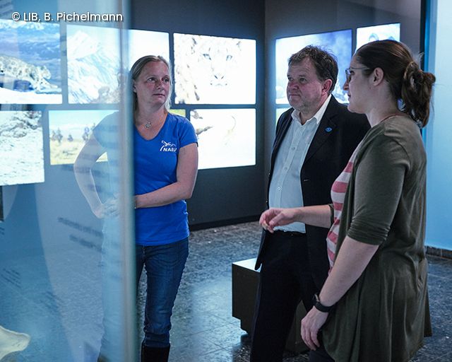 3 Menschen im Gespräch vor Ausstellungsvitrine